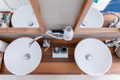 a bathroom with two white sinks and mirrors at Cumeja Beach Club & Hotel in Baia Domizia