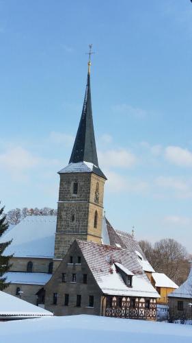 a church with a tall steeple in the snow at Appartement Fleischmann in Kirchröttenbach