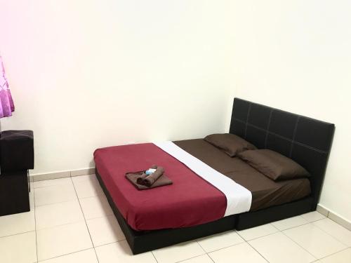 a bedroom with a bed with a black and red comforter at PD Perdana Homestay Pool side in Port Dickson