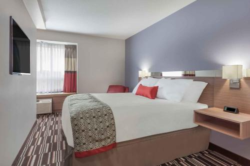 a hotel room with a large bed and a television at Microtel Inn & Suites by Wyndham Fort McMurray in Fort McMurray