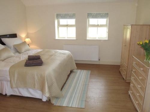 a bedroom with a bed and a dresser and two windows at Little welham in Bedale
