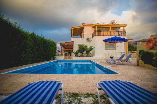 una casa con piscina y 2 sillas azules en Thomas Villa 5, en Argaka