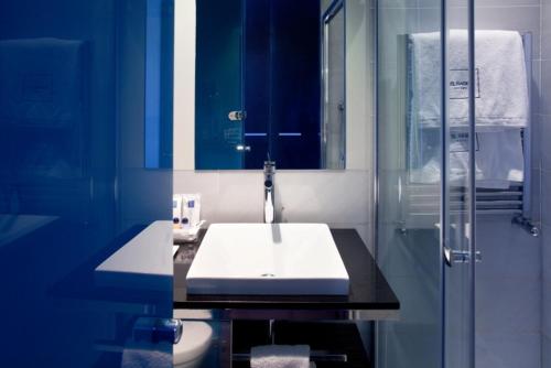 a bathroom with a sink and a toilet and a mirror at Hotel El Raset in Denia