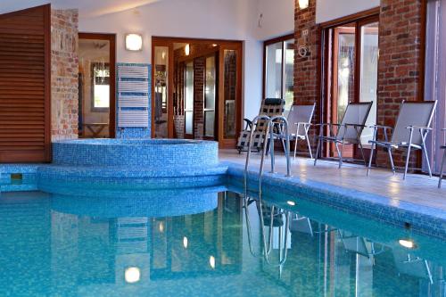 a swimming pool with chairs and tables in a building at Woodland Villa in Gyula