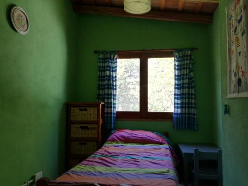 Dormitorio verde con cama y ventana en Espejo Escondido in 