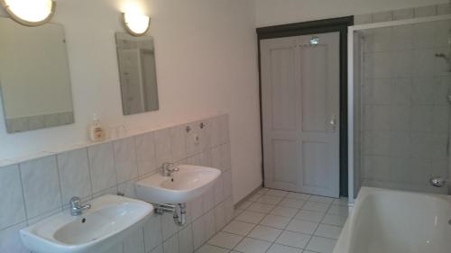 a bathroom with two sinks and a tub and a mirror at Gaststätte und Pension Felsenthal in Tabarz