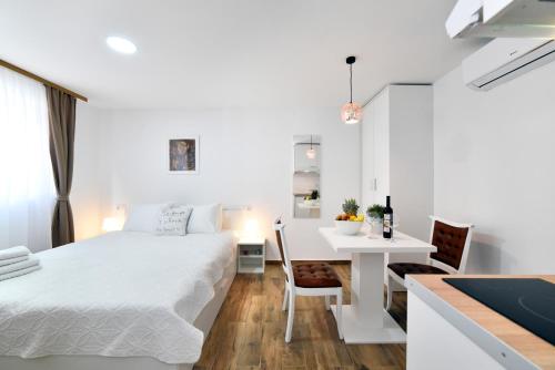a white bedroom with a white bed and a desk at Piccolo Apartments in Zagreb