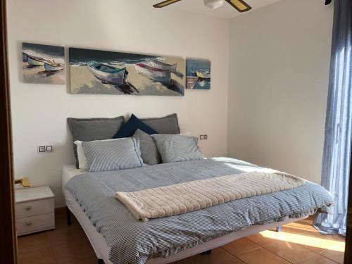 ein Schlafzimmer mit einem Bett mit drei Gemälden an der Wand in der Unterkunft Casa Serenity in Lajares