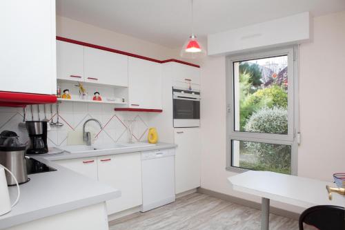 une cuisine avec des armoires blanches et une fenêtre dans l'établissement Les Terrasses De La Comtesse, à Saint-Quay-Portrieux