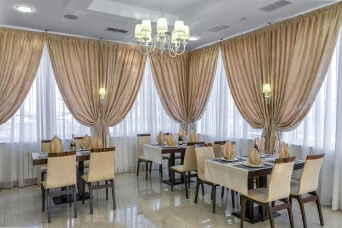 a dining room with tables and chairs and windows at Alarus Luxe Hotel in Odesa