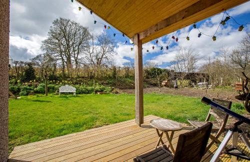 a wooden deck with a table and chairs on a yard at Ty'r Afon - River Cottage in Bala