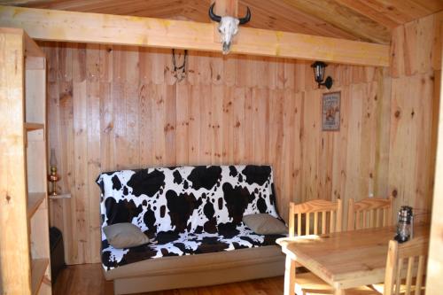 a black and white cow couch in a wooden room at Le Ranch Amadeus in Saint-Paul-en-Born
