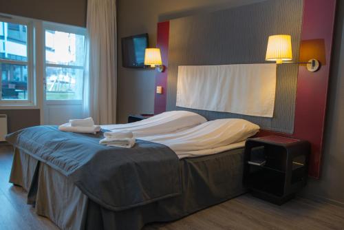 a bed in a hotel room with two towels on it at Oppdal Gjestetun Hotell in Oppdal