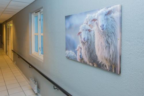 a painting of three sheep hanging on a wall at Oppdal Gjestetun Hotell in Oppdal
