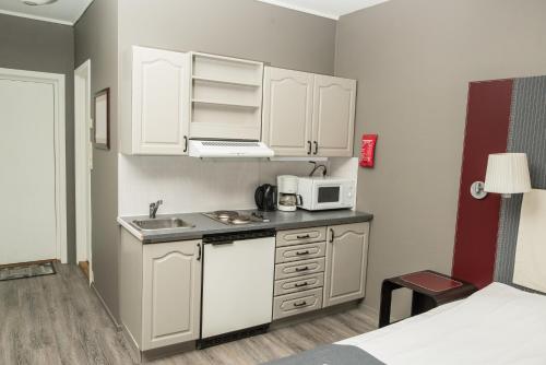 a small kitchen with white cabinets and a microwave at Oppdal Gjestetun Hotell in Oppdal