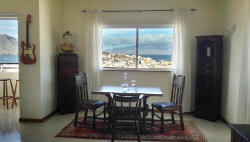 a dining room with a table and chairs and a window at Bouganville in Mindelo