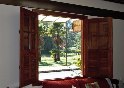 ein offenes Fenster mit Blick auf eine Palme in der Unterkunft Chalé do Lago in Araxá