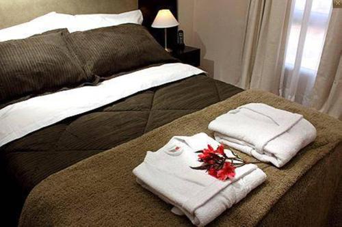 Una cama con toallas y flores encima. en De Los Arroyos Apart Hotel en San Nicolás de los Arroyos