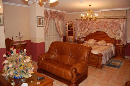 a bedroom with a bed and a leather couch at Hotel Flor de la Mancha in La Roda