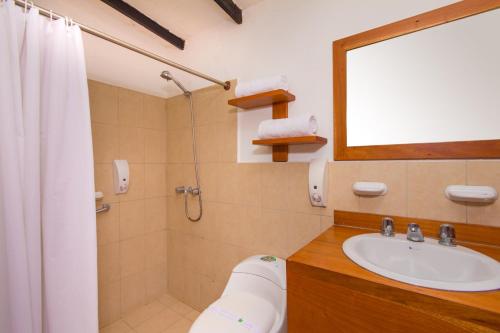 a bathroom with a sink and a toilet and a mirror at Hotel Fiesta in Puerto Ayora