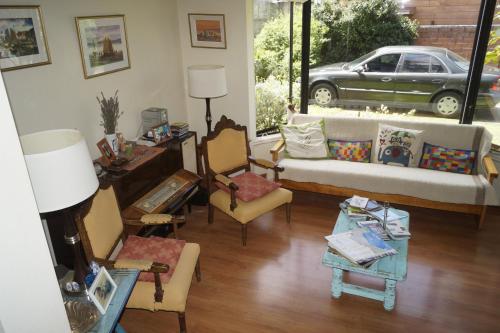 a living room with a couch and chairs and a car at Hospedaje El Roble, Puerto Varas in Puerto Varas