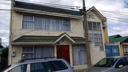 a house with a red door and two cars parked in front at Hostal El Toque de Pilar in Punta Arenas