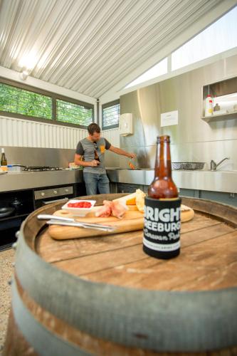 a person in a kitchen with a bottle of beer at Discovery Parks - Bright in Bright