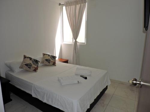 Schlafzimmer mit einem weißen Bett und einem Fenster in der Unterkunft Apartamento Santamore II in San Gil