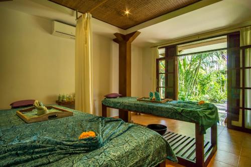 a room with two beds and a table with a window at Villa Sonia Ubud in Ubud