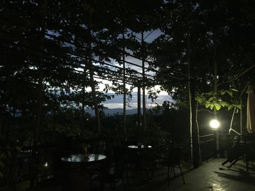 a patio with tables and chairs at night at Baan Rai Phufah Resort Chiangrai in Ban Pa Ruak