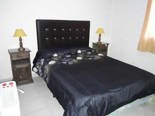 a bedroom with a black bed with two night stands at Cabañas Santa Teresita in Potrerillos