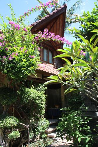 a house with pink flowers on the side of it at Blue Star Bungalows & Cafe in Amed