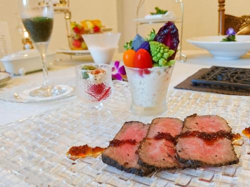 a table with a piece of meat and a salad at Chez-soi Wakamiya in Gujo