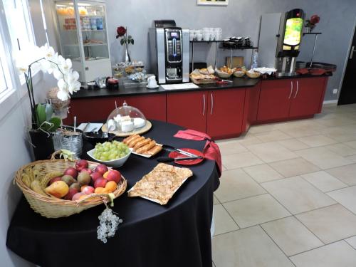 a table topped with a basket of fruit and snacks at Hotel Air-lane in Saint-Léger-sous-Brienne
