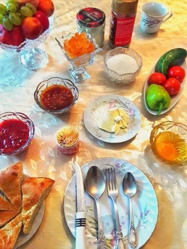 a table with plates and utensils and other food at RAHAT Guest House & Hostel in Toktogul in Toktogul