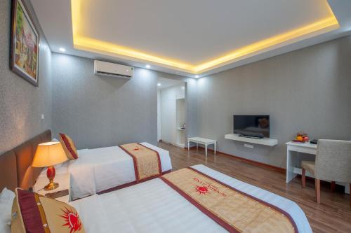 a hotel room with two beds and a television at Sunrise Hanoi Hotel in Hanoi