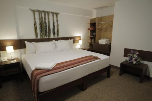 a bedroom with a large white bed with two tables at Tierra Viva Puno Plaza in Puno
