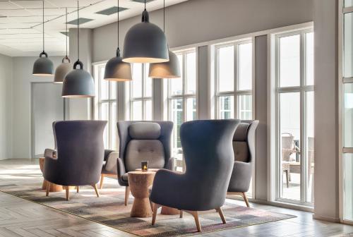 a lobby with chairs and a table and windows at Quality Hotel Skjærgården in Langesund