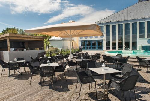 a patio with tables and chairs and an umbrella at Quality Hotel Skjærgården in Langesund