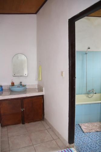 La salle de bains est pourvue d'un lavabo, d'une baignoire et d'un miroir. dans l'établissement Blue Star Bungalows & Cafe, à Amed