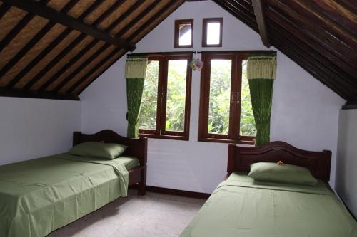 dwa łóżka w pokoju z oknami w obiekcie Blue Star Bungalows & Cafe w mieście Amed