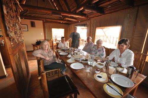 Twee RivierenにあるXaus Lodgeの木のテーブルの周りに座る人々