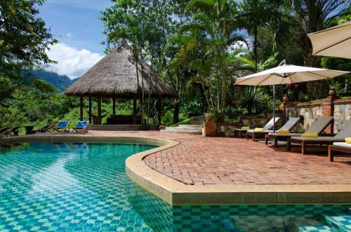 a swimming pool with chairs and umbrellas next to a resort at Hillside - Nature Lifestyle Lodge in Luang Prabang