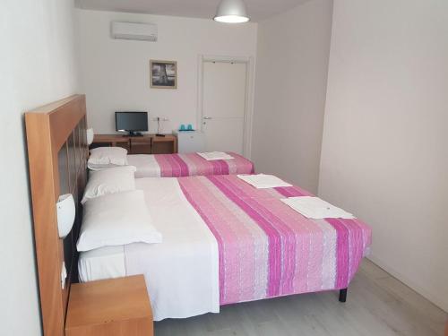 1 dormitorio con 2 camas y TV. en Desiderio Monolocali e camere, en Lido Adriano