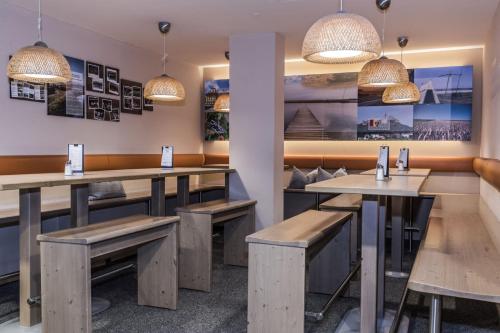 a restaurant with wooden tables and benches and lights at JUFA Hotel Altenmarkt-Zauchensee in Altenmarkt im Pongau