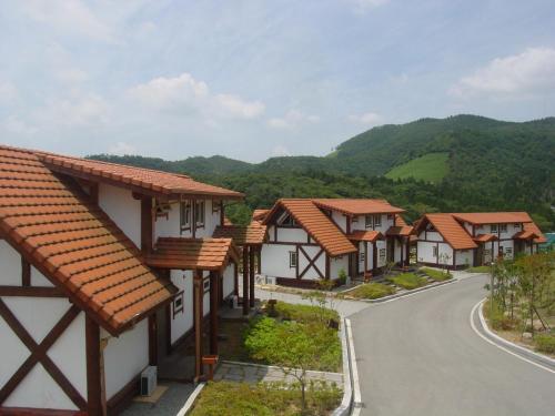 a row of houses on a road with mountains in the background at 보성녹차리조트 in Boseong