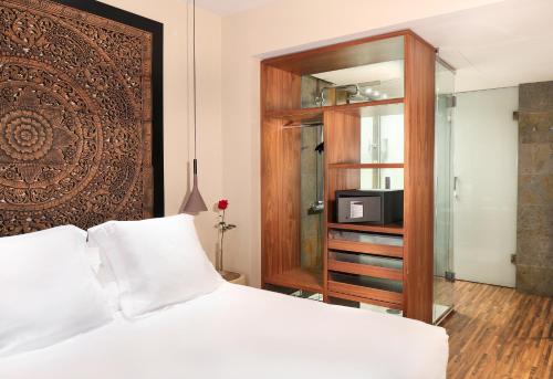 巴塞罗那Hotel Gran Derby Suites, a Small Luxury Hotel of the World的一间卧室配有一张床和一个带微波炉的橱柜