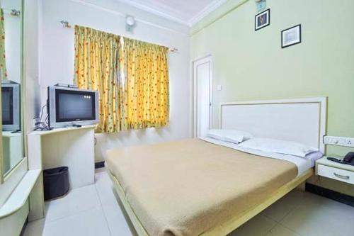 Habitación blanca con cama y TV en The Corporate Comforts, en Bangalore