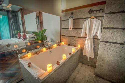 uma casa de banho com uma banheira com velas e um roupão em The Night Hotel em Siem Reap