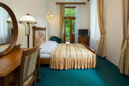 Schlafzimmer mit einem Bett, einem Spiegel und einem Schreibtisch in der Unterkunft Spa Resort Libverda - Villa Friedland in Bad Liebwerda